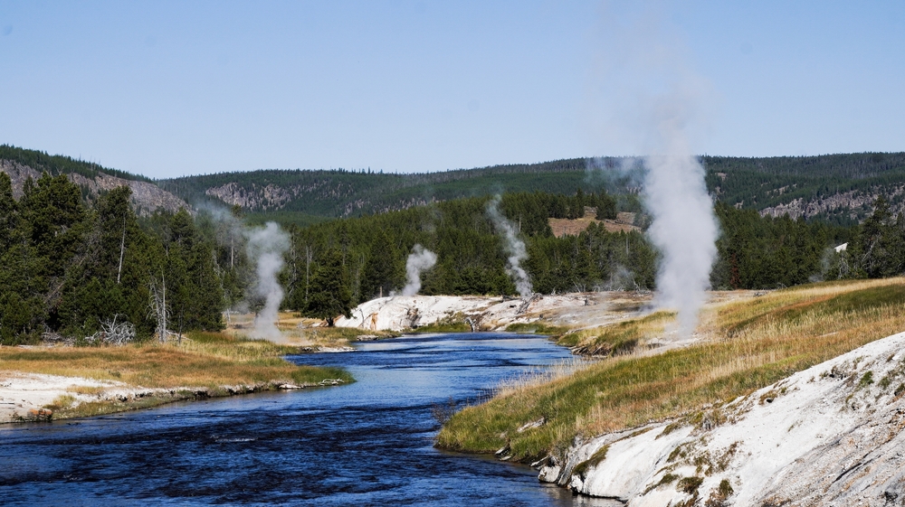 A,serene,river,winds,through,yellowstone's,geothermal,landscape.,steam,rises