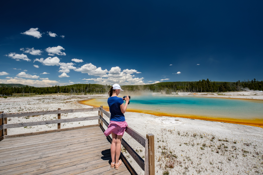 Woman,tourist,with,camera,overlooking,hot,thermal,spring,sunset,lake